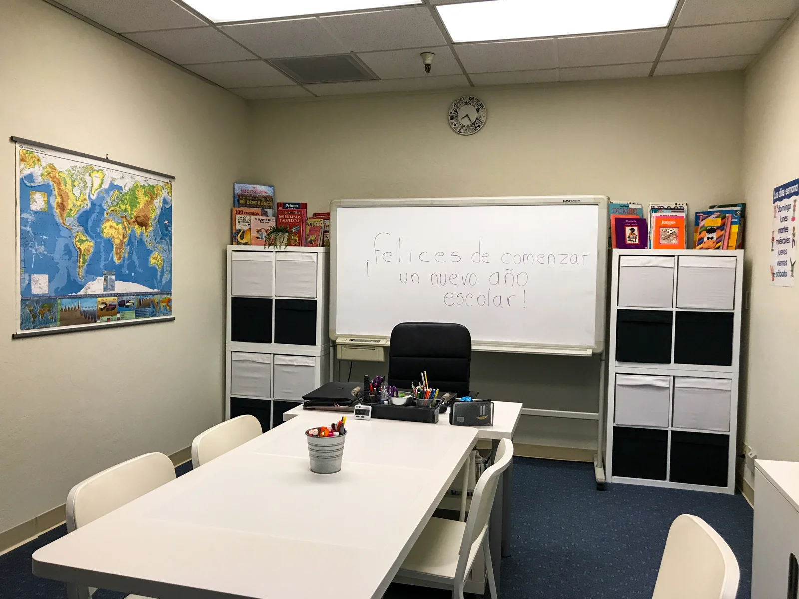 Learning tables, Spanish materials, and a whiteboard at the center